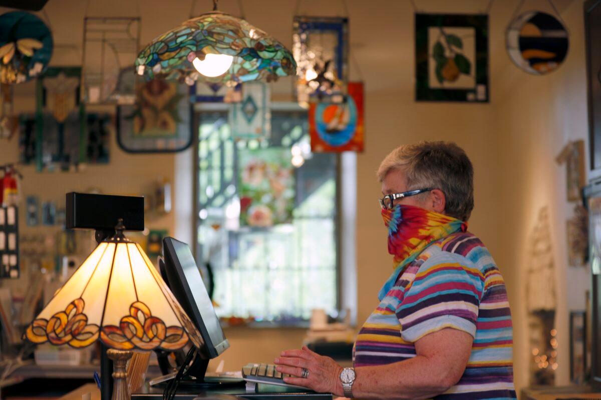 Vicki Driscoll works behind the counter at The Glass Workbench glass and gift shop in St. Charles, Mo., on May 4, 2020. (Jeff Roberson/AP Photo)