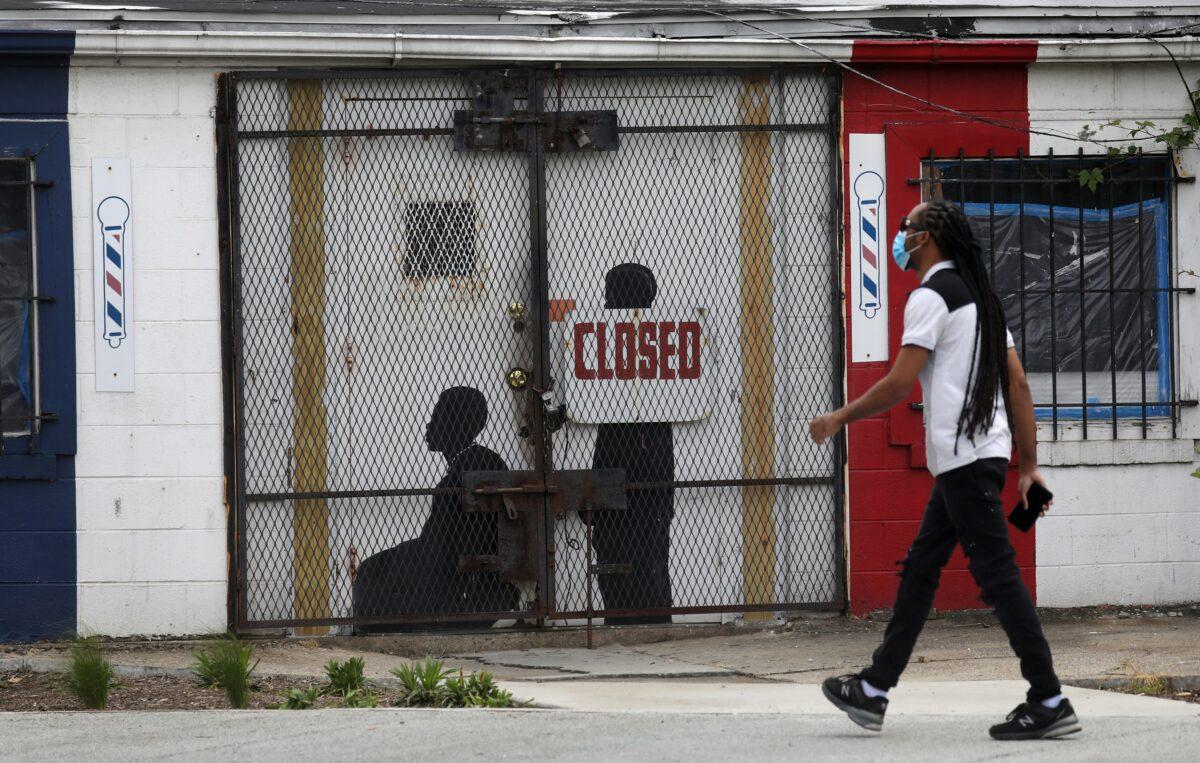 A pedestrian walks past a closed barbershop in Ward 7 as the CCP virus outbreak continues in Washington on May 8, 2020. (Leah Millis/Reuters)