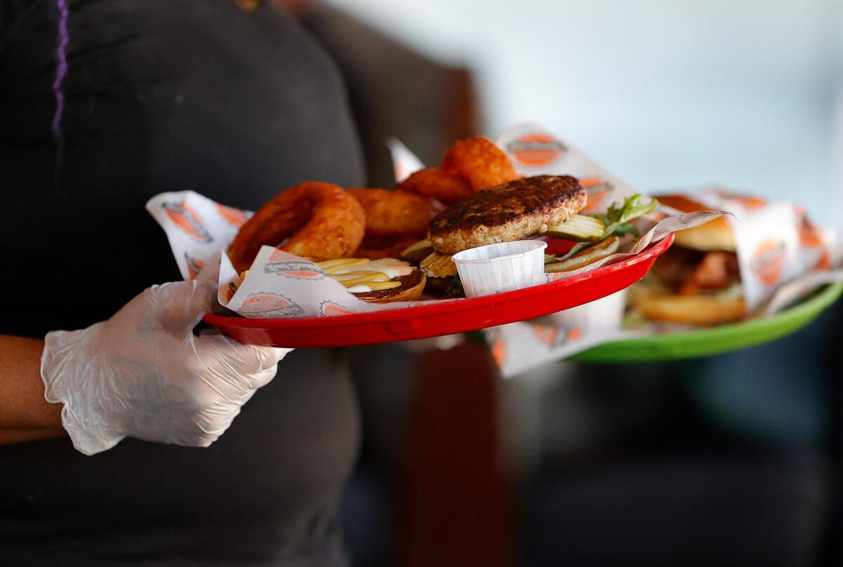 A server is seen delivering food wearing disposable gloves in Bad Daddy's Burger Bar as it reopened for dine-in seating in Decatur, Ga., on April 27, 2020. (Kevin C. Cox/Getty Images)