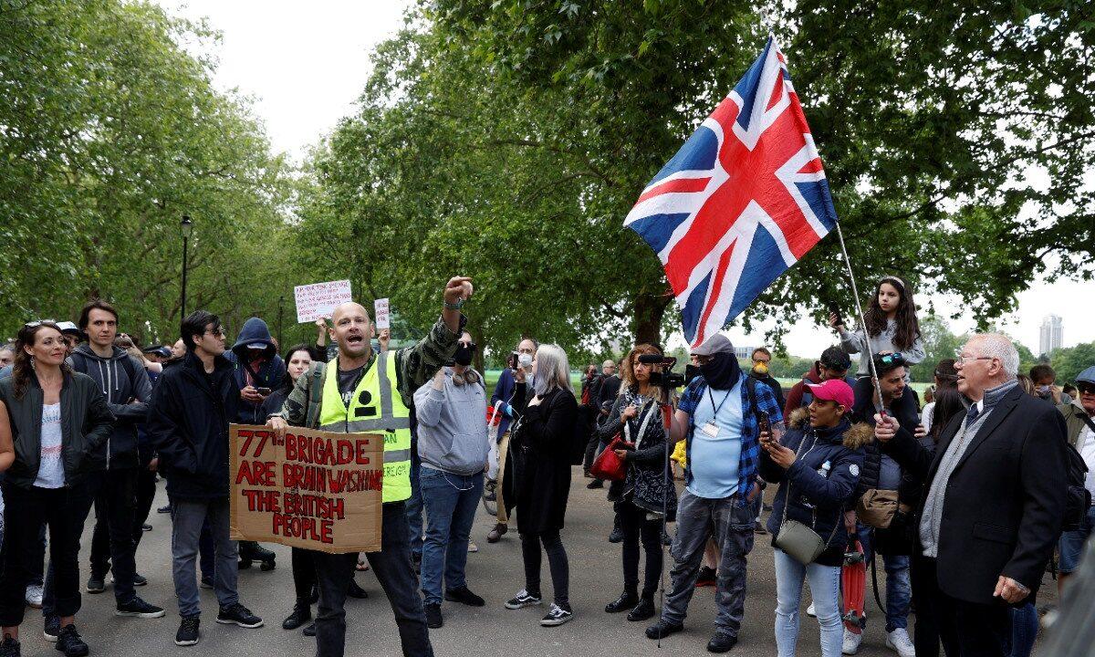 People hold up banners and a union jack flag in protest against lockdown and vaccination in Hyde Park, following the outbreak of COVID-19, London, Britain, on May 16, 2020. (John Sibley/Reuters)
