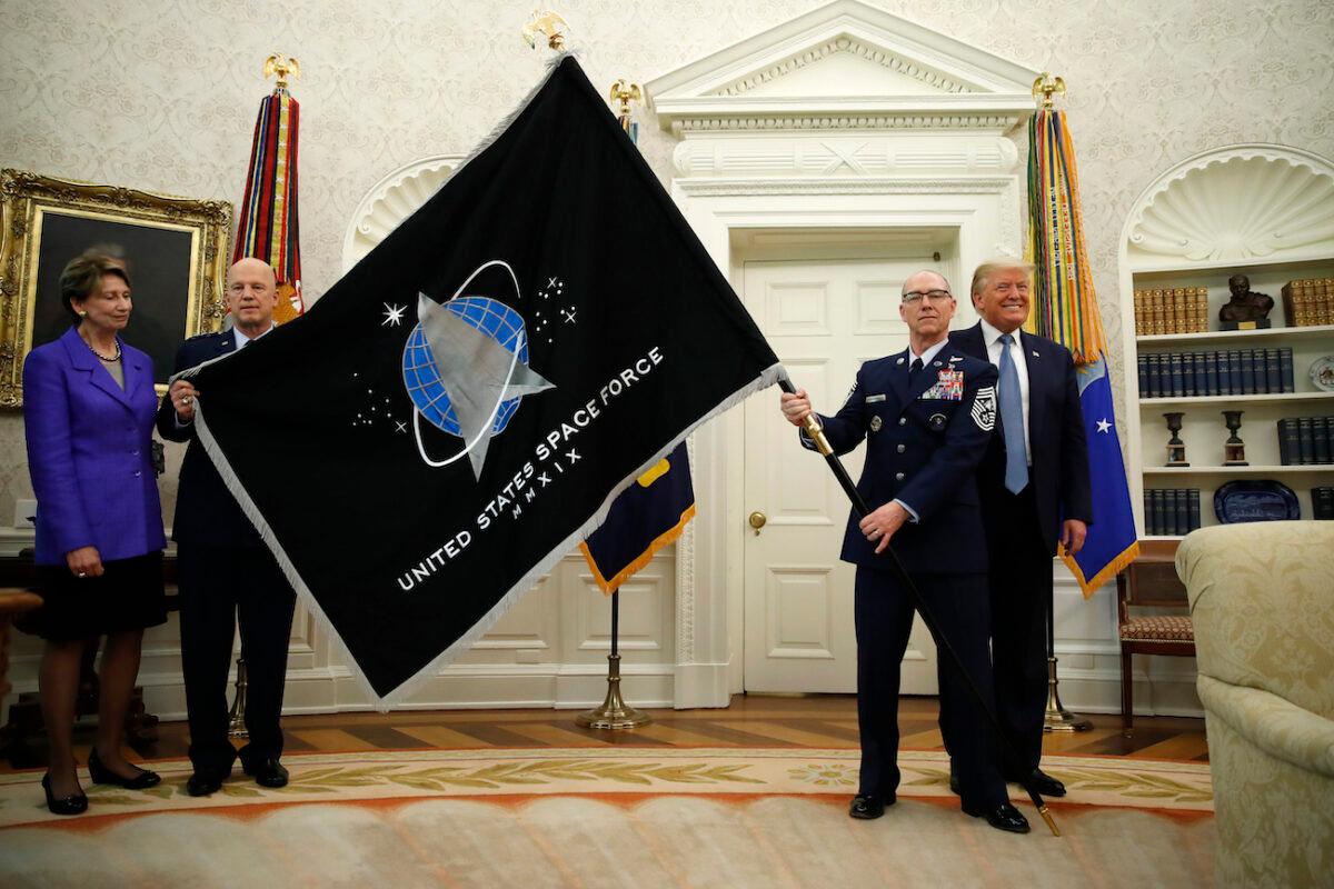 President Donald Trump stands as Chief of Space Operations at US Space Force Gen. John Raymond, second from left, and Chief Master Sgt. Roger Towberman, second from right, hold the United States Space Force flag as it is presented in the Oval Office of the White House, Friday, May 15, 2020, in Washington. Secretary of the Air Force Barbara Barrett stands far left. (Alex Brandon/AP Photo)