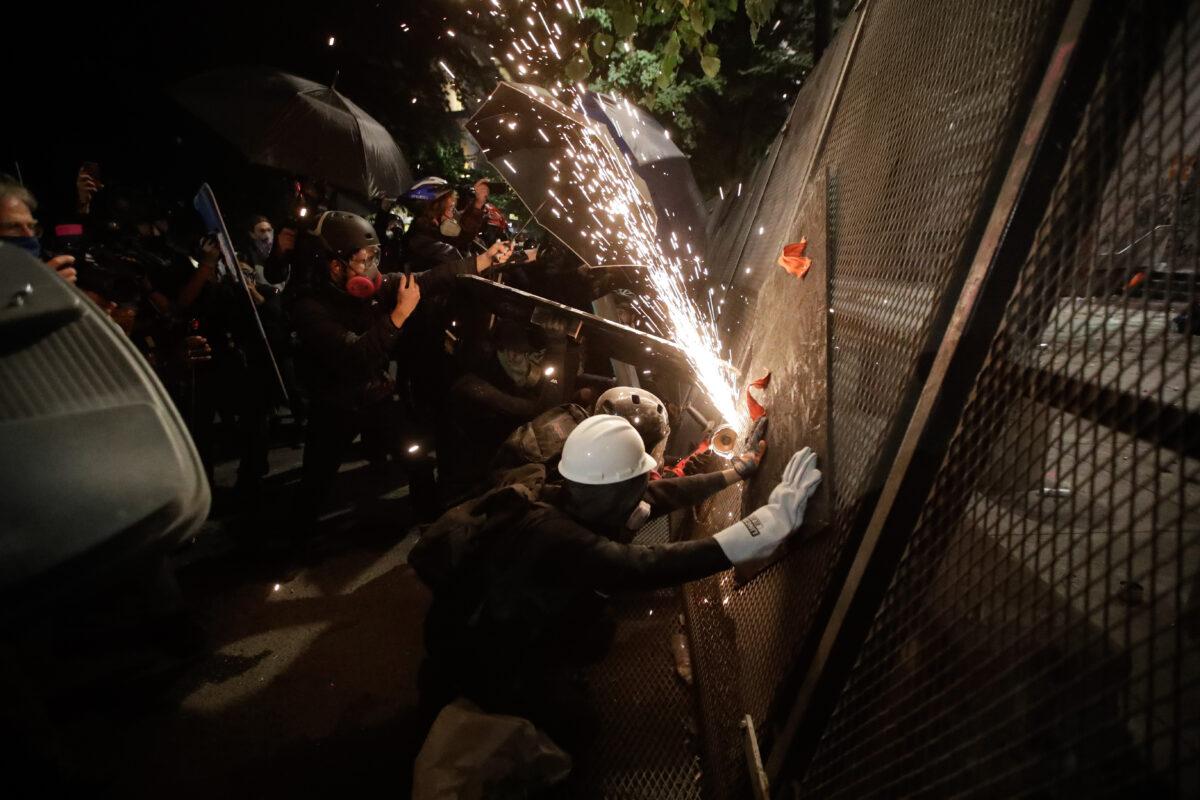 People try to cut through a steel fence protecting the Mark O. Hatfield Courthouse in Portland, Ore., on July 24, 2020. (Maricio Jose Sanchez/AP Photo)