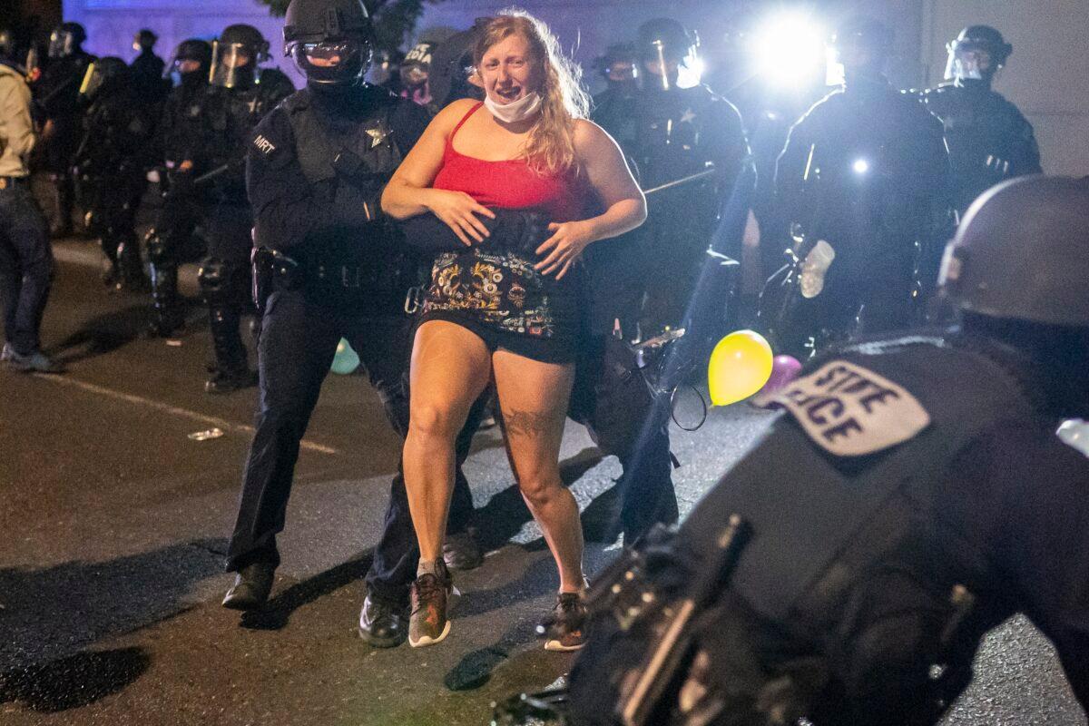 Oregon State Troopers drag a woman behind the police line while dispersing a riot in Portland, Ore., on Sept. 4, 2020. (Nathan Howard/Getty Images)