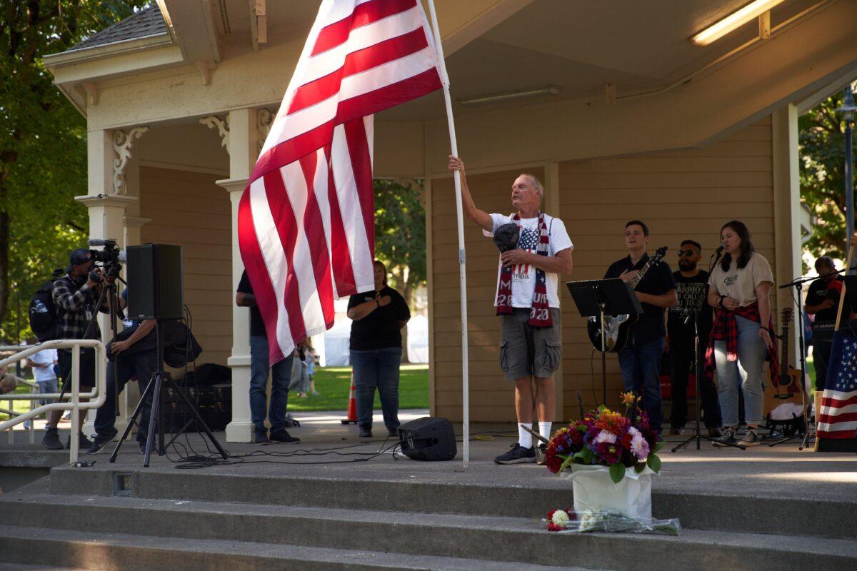 A man waves an American flag during the national anthem as members and supporters of Patriot Prayer gather in Esther Short Park for a memorial for Aaron Danielson in Vancouver, Wash., on Sept. 5, 2020. (Allison Dinner/AFP via Getty Images)