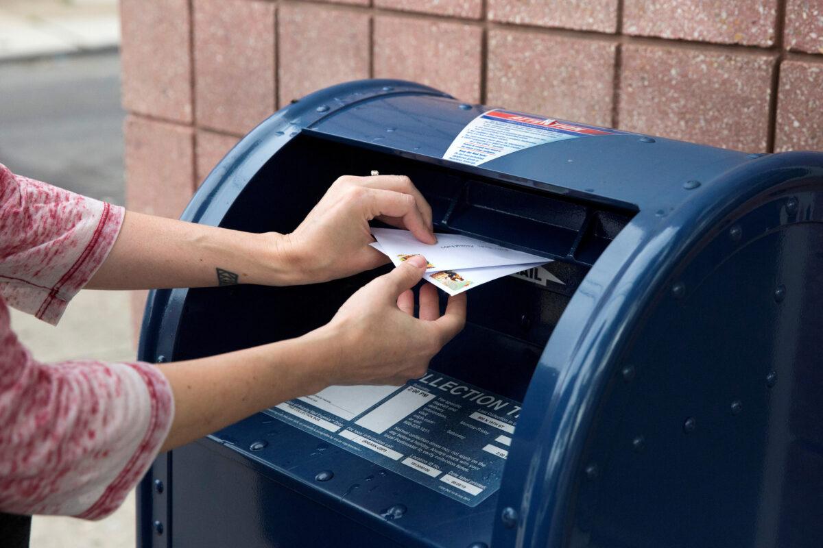 An individual deposits letters into a U.S. Postal Service collection mailbox in Philadelphia, Penn., on Aug. 14, 2020. (Rachel Wisniewski/Reuters)