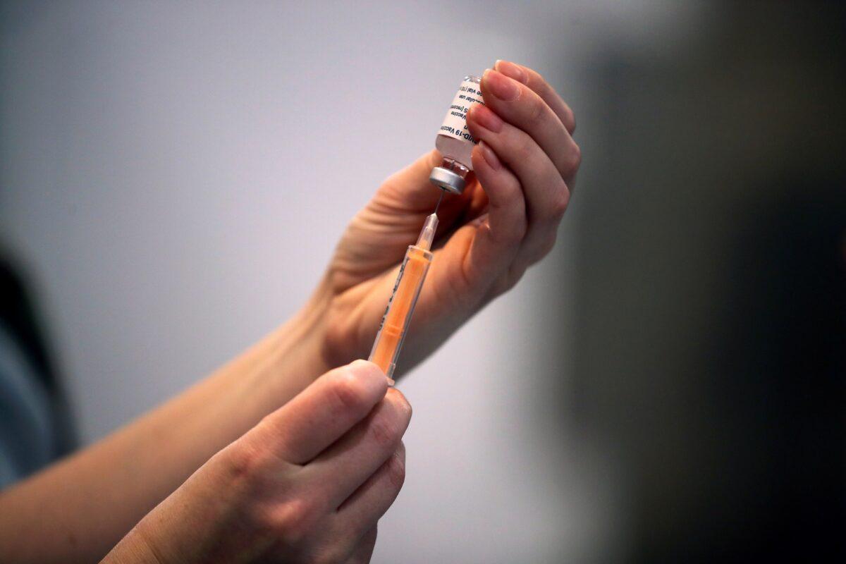 A health care worker prepares a dose of a COVID-19 vaccine at a vaccination center inside the Blackburn Cathedral, United Kingdom, on Jan. 19, 2021. (Molly Darlington/Reuters)