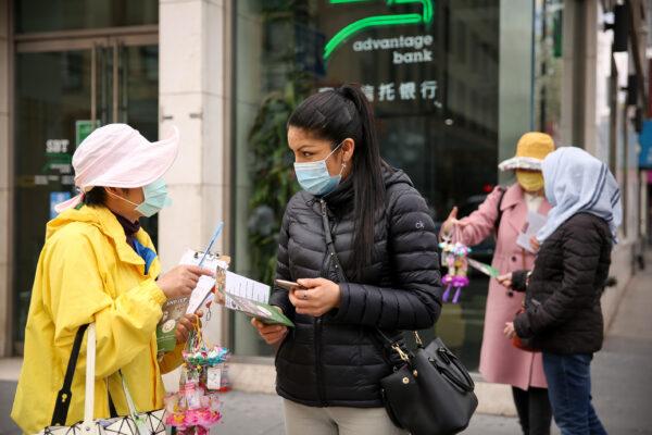 Falun Gong practitioners talk to passers-by as they take part in a parade in Flushing, New York, on April 18, 2021, to commemorate the 22nd anniversary of the April 25th peaceful appeal of 10,000 Falun Gong practitioners in Beijing. (Samira Bouaou/The Epoch Times)