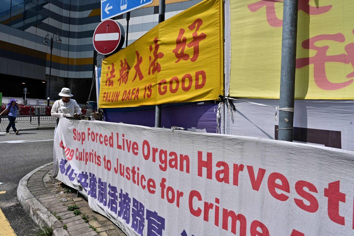 A woman adjusts banners in support of the Falun Gong spiritual discipline, which is persecuted in mainland China, in Tung Chung, an area popular with tourists from the mainland, in Hong Kong on April 25, 2019. (Anthony Wallace/AFP via Getty Images)