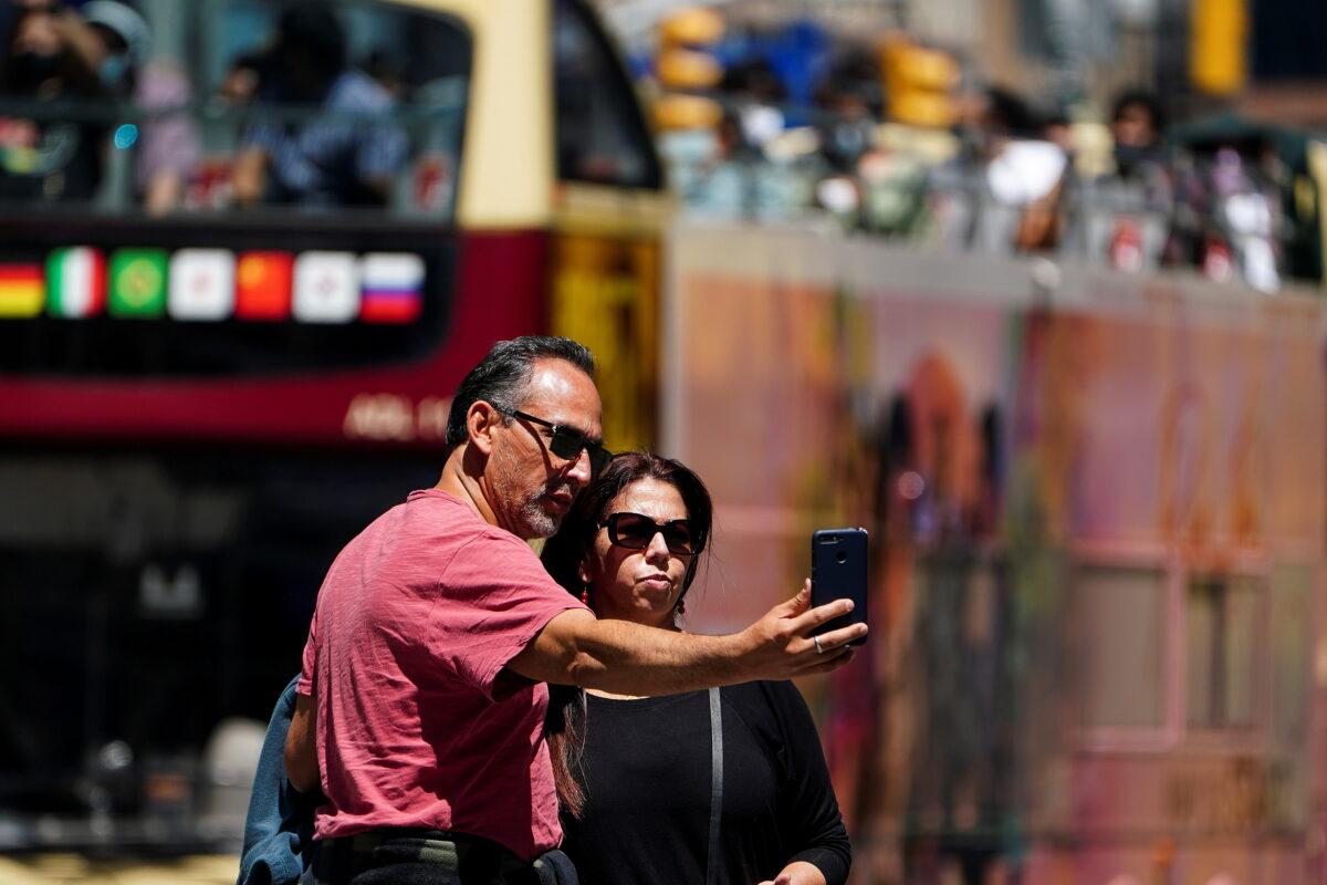 People with no masks pose for photos in Times Square in the Manhattan borough of New York City on May 14, 2021. (Carlo Allegri/Reuters)