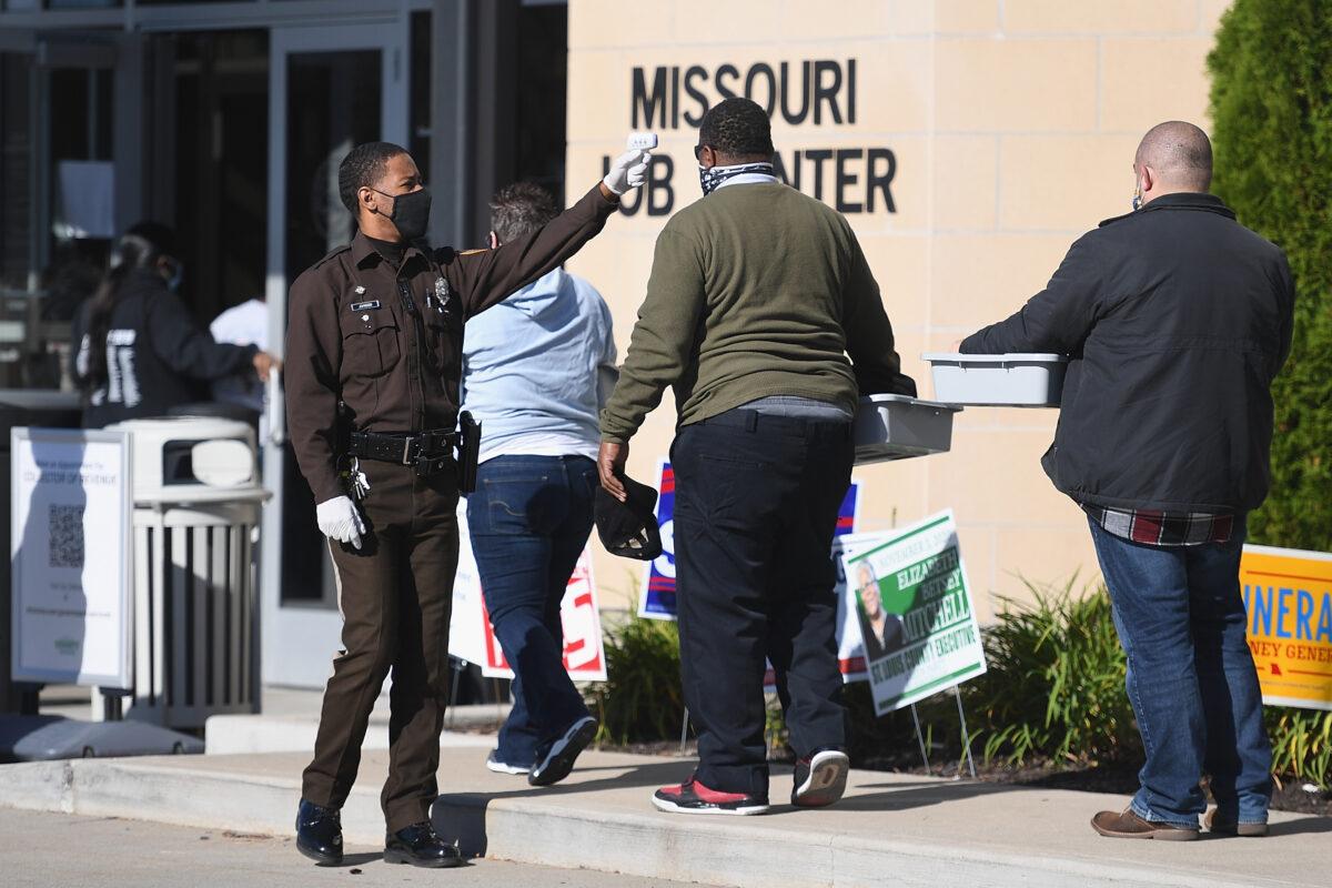 A Law Enforcement Officer temperature screens voters as they wait in line to cast their ballots at the St. Louis County Board of Elections in St. Ann, Mo., on Nov. 3, 2020. (Michael B. Thomas/Getty Images)