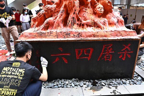 A student before the Pillar of the Shame in Hong Kong, on June 4, 2021. The statue’s base shows the words “June 4th Massacre.” (Sung Pi-lung/The Epoch Times)