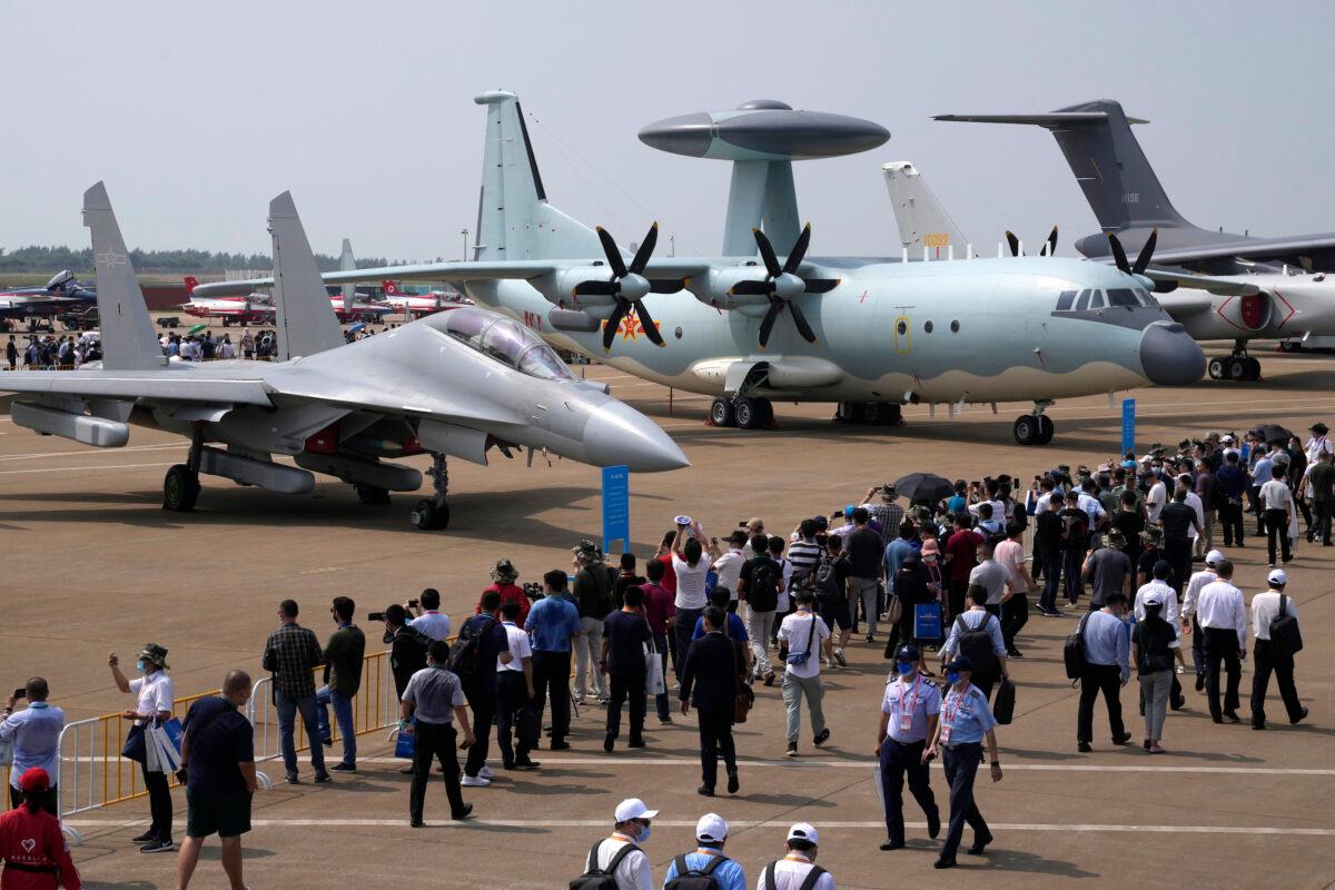 Visitors look at the Chinese military’s J-16D electronic warfare airplane (L) and the KJ-500 airborne early warning and control aircraft (R) during the 13th China International Aviation and Aerospace Exhibition in Zhuhai, Guangdong Province, China, on Sept. 29, 2021. (Ng Han Guan/AP Photo)