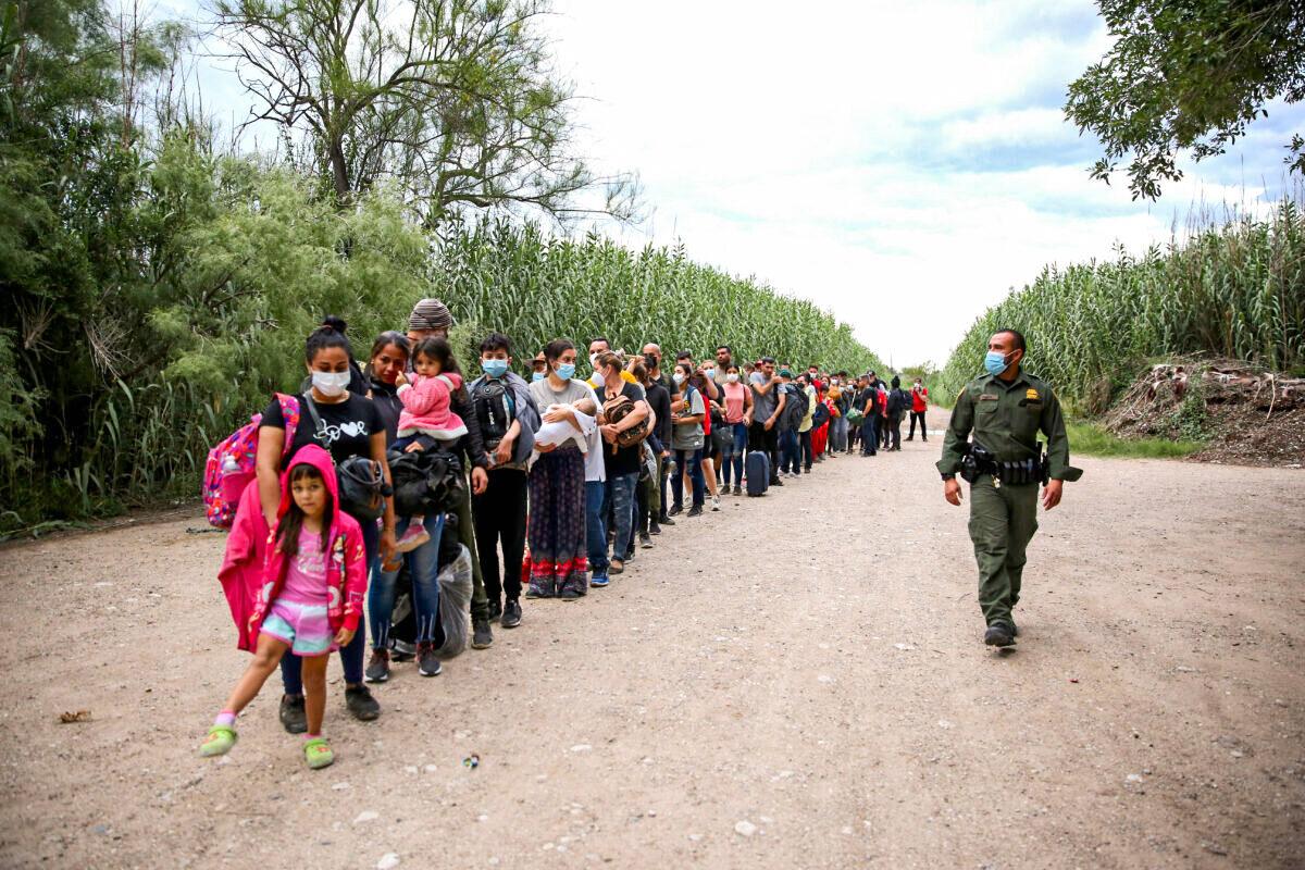 A group of Venezuelans wait to be picked up by Border Patrol after illegally crossing the Rio Grande from Mexico into Del Rio, Texas, on June 3, 2021. (Charlotte Cuthbertson/The Epoch Times)