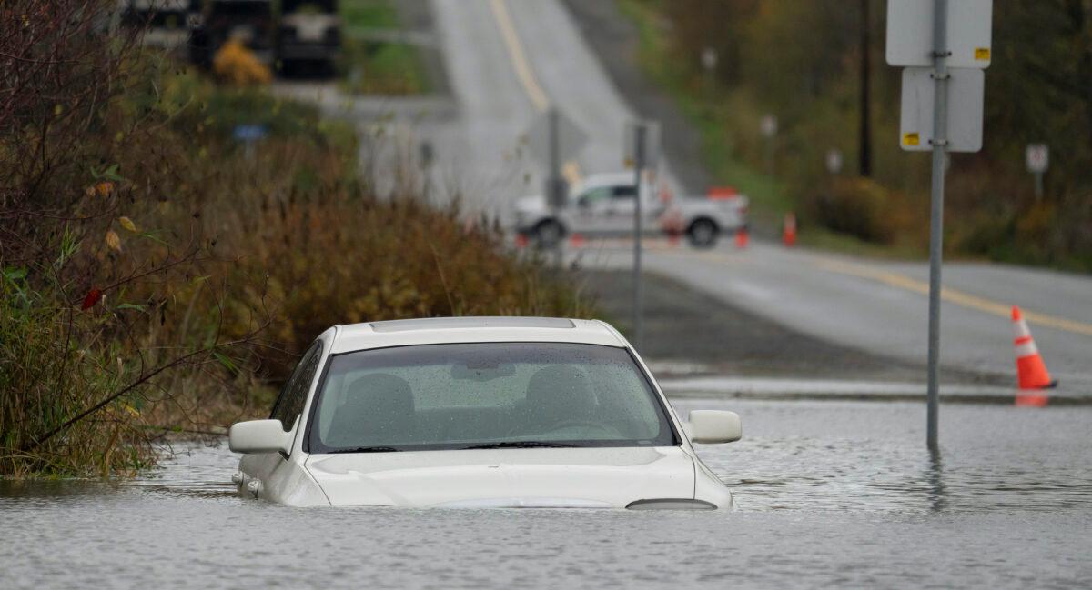 A vehicle is submerged in flood waters along a road in Abbotsford, B.C., on Nov. 15, 2021. (Jonathan Hayward/The Canadian Press)