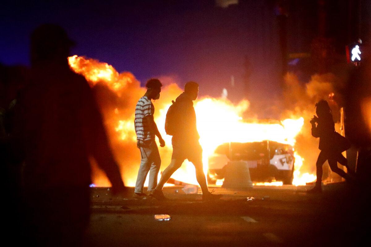 Demonstrators walk in front of a police car that has been lit on fire during a protest in Boston on May 31, 2020, in response to the death of George Floyd. (Maddie Meyer/Getty Images)