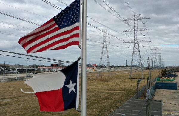The U.S. and Texas flags fly in front of high-voltage transmission towers in Houston on Feb. 21, 2021. (Justin Sullivan/Getty Images)