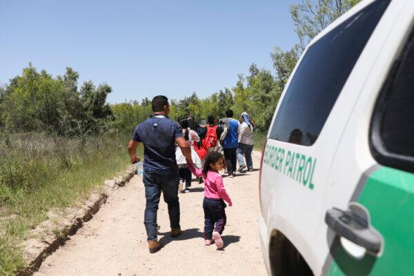 A group of illegal aliens walks up the road after crossing the Rio Grande from Mexico. Further up the road, they will board a bus bound for the Border Patrol processing facility in McAllen, Texas, on April 18, 2019. (Charlotte Cuthbertson/The Epoch Times)