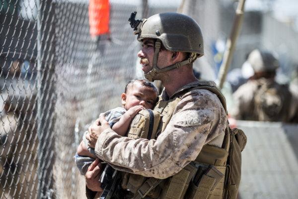 A Marine calms a child during an evacuation at Hamid Karzai International Airport, Kabul, Afghanistan, on Aug. 26, 2021. (Sgt. Samuel Ruiz, U.S. Marine Corps)