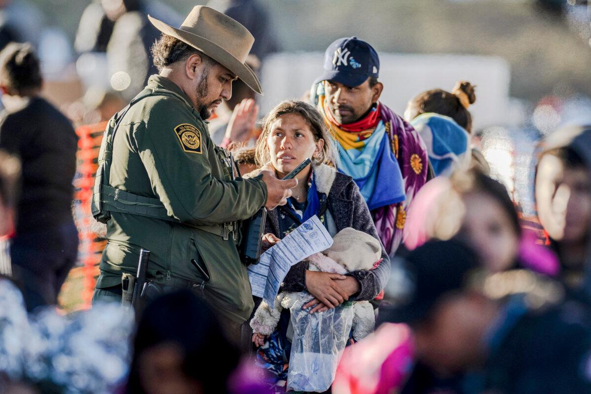 A U.S. Border Patrol agent speaks with illegal immigrants at a transit center near the U.S.–Mexico border in Eagle Pass, Texas, on Dec. 19, 2023. (John Moore/Getty Images)