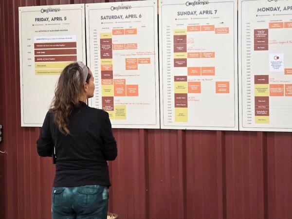 A visitor looks over the day's schedule at Confluence 2024 in Bandera, Texas, on April 5, 2024. (Allan Stein/The Epoch Times)