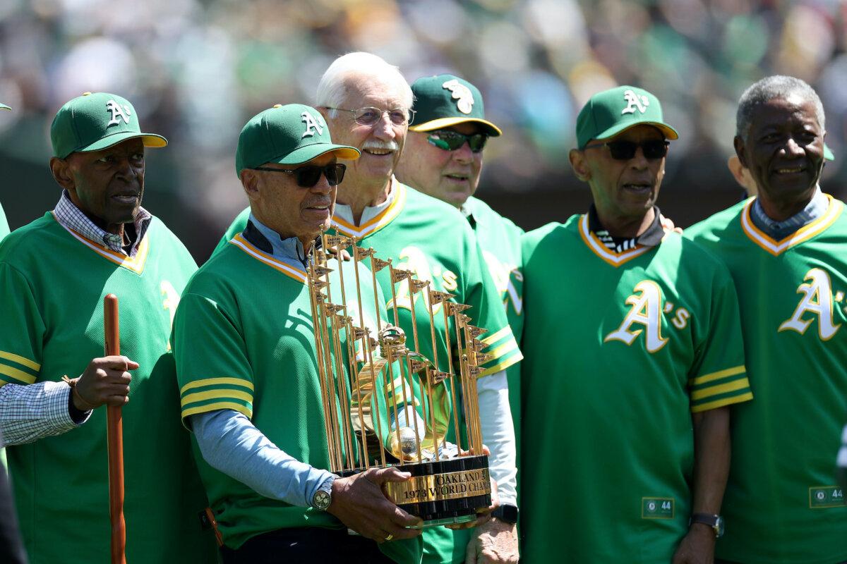 Reggie Jackson holds the World Series trophy while he poses with teammates during a ceremony honoring the 50-year reunion of the World Series Champions 1973 Oakland Athletics before the Oakland Athletics game against the New York Mets at RingCentral Coliseum in Oakland, Calif., on April 16, 2023. (Ezra Shaw/Getty Images)